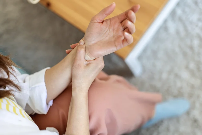 Frau mit Polyarthritis hält sich das schmerzende Handgelenk