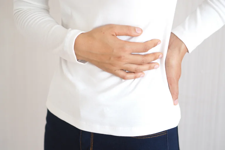 Eine Frau hält sich den Bauch, in dem sich auch die Milz befindet, direkt unter dem Zwerchfell.