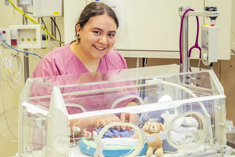 Pflegefachkraft versorgt ein neugeborenes Baby in einem Inkubator.
