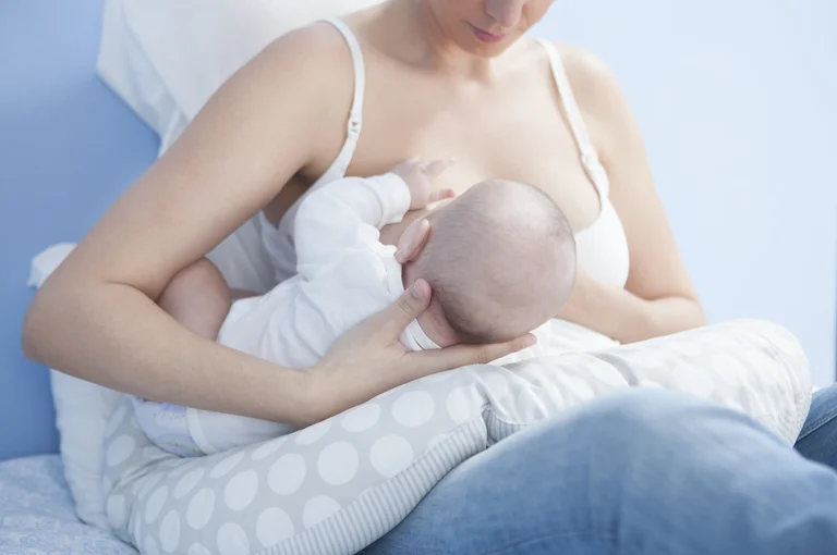 Frau hält ihr Baby zum Stillen an die Brust