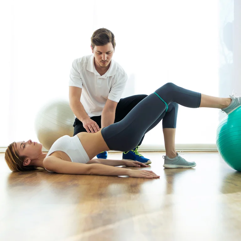 Physiotherapeut unterstützt eine Patientin bei einer Übung