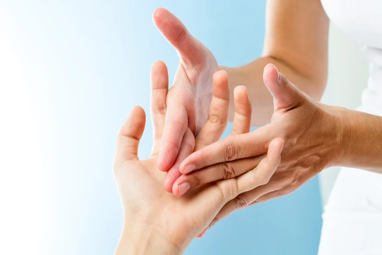 Ärztin tastet die Hand eines Kindes mit den Händen ab.