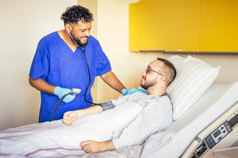 Eine Pflegekraft misst bei einem Patienten den Bluthochdruck