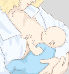 Eine Mutter stillt ihr Kind im Wiegegriff.